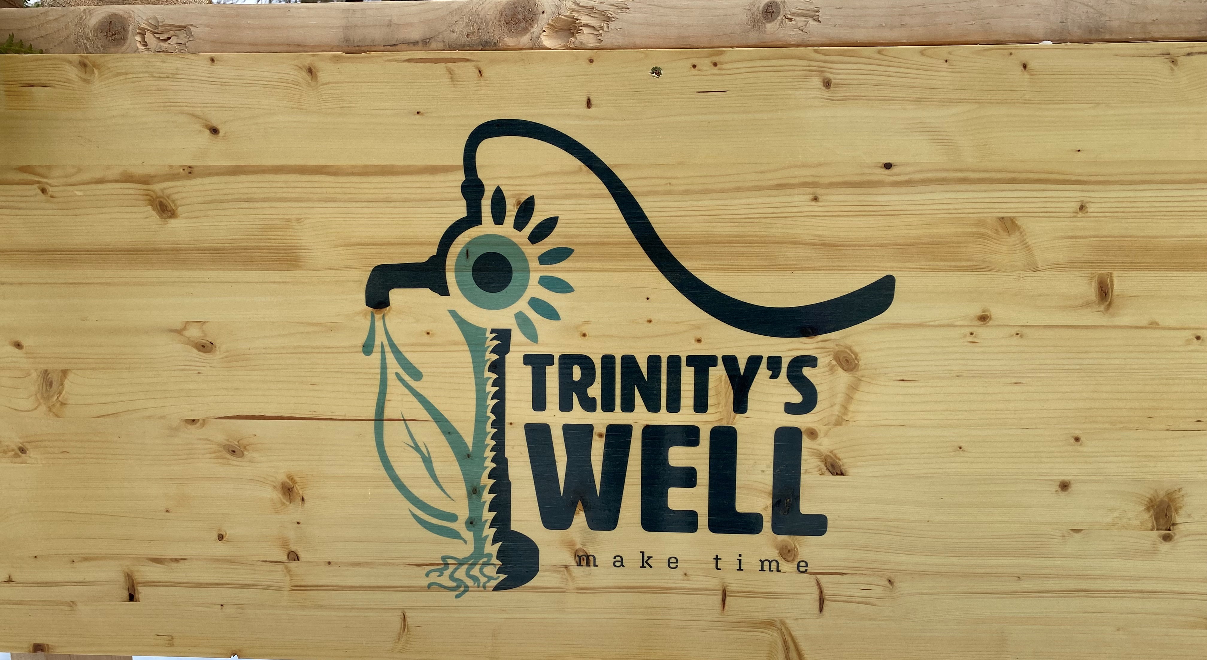 Trinity's Well logo on wood