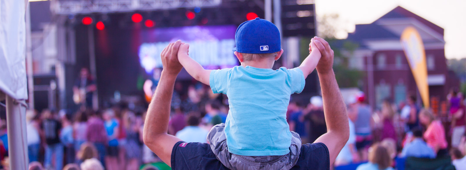 boy on man's shoulders watching a concert