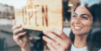 Woman placing an open for business sign on a window